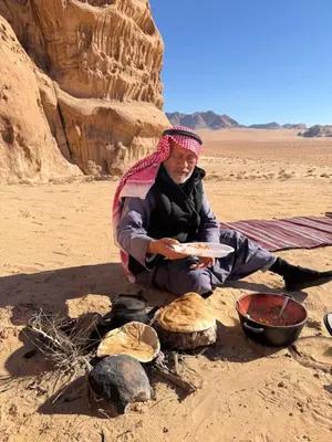 a woman sitting in the desert with a plate of food at Bedouin Desert Life Camp & Jeep Tours in Wadi Rum