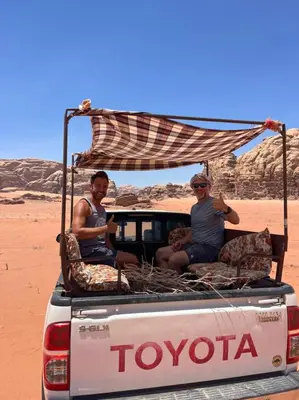 two people sitting in the back of a truck in the desert at Wadi Rum Star Camp in Wadi Rum