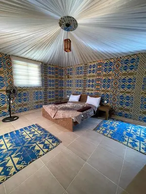 a bedroom with a bed and blue and yellow tiles at Wadi Rum Star Camp in Wadi Rum