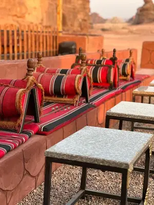 a row of benches with red pillows on them at Wadi Rum Star Camp in Wadi Rum