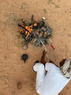 a man standing in the dirt with a pile of food at Enad desert camp in Wadi Rum