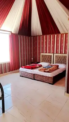 two beds in a room with red and white walls at Enad desert camp in Wadi Rum