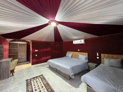 a bedroom with two beds and a red wall at Jabal Rum Camp in Wadi Rum