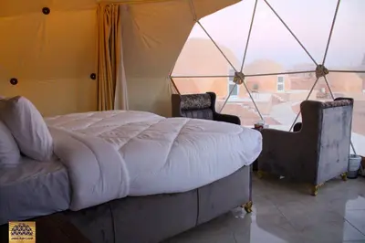 a bedroom with a bed and two chairs in a tent at Jabal Rum Camp in Wadi Rum