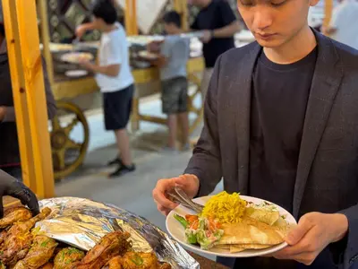 a man holding a plate of food with a plate of food at Jabal Rum Camp in Wadi Rum