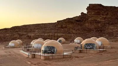 a group of domes in a desert with a mountain at Jabal Rum Camp in Wadi Rum