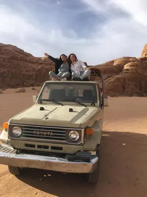 two women sitting on the back of a truck in the desert at Wadi Rum Desert Stars in Wadi Rum
