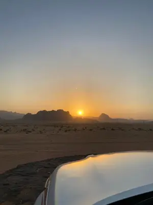 a car parked in the desert with the sunset at Allen Luxury Wadi Rum in Wadi Rum
