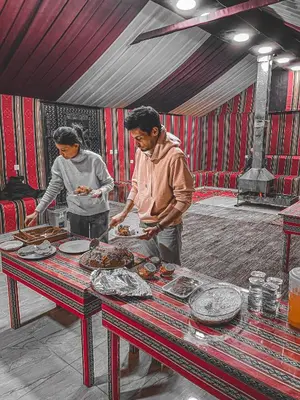 a man and a woman preparing food in a tent at Allen Luxury Wadi Rum in Wadi Rum