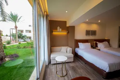 a hotel room with two beds and a window at Luxotel Aqaba Beach Resort & Spa Only 15 years plus in Aqaba