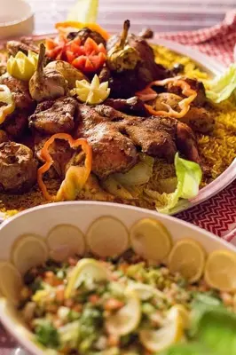 a plate of food with meat and vegetables on a table at Wadi rum under stars in Wadi Rum