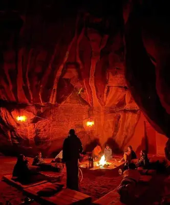 a group of people sitting around a fire in a cave at Wadi rum under stars in Wadi Rum