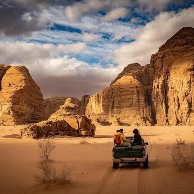 two people riding in the back of a truck in the desert at Wadi rum under stars in Wadi Rum