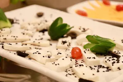 a plate of food with cheese and a tomato at Luciana Hotel by FHM in Aqaba