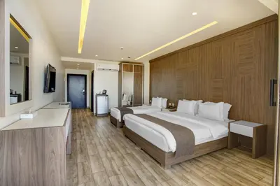 a hotel room with two beds and a television at Luciana Hotel by FHM in Aqaba