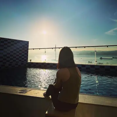 a woman sitting next to a pool watching the sunset at ALENA HOTEL in Aqaba