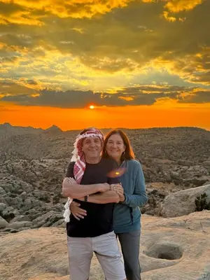 a man and a woman posing for a picture with the sunset at 7 Caves Hotel in Al Jāyah