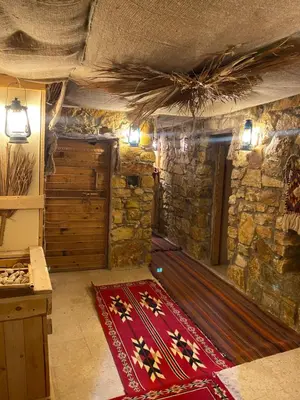 a room with a red rug on a stone wall at 7 Caves Hotel in Al Jāyah