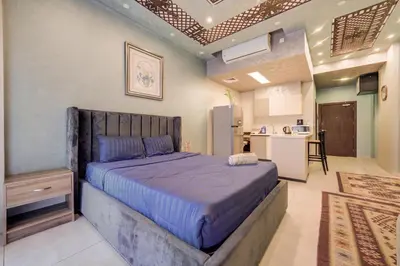 a bedroom with a large bed and a kitchen at Al Raha Village - Aqaba in Aqaba