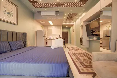 a bedroom with a large bed and a kitchen at Al Raha Village - Aqaba in Aqaba