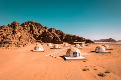 a row of domes in the desert with rocks at Star Magic Camp in Wadi Rum