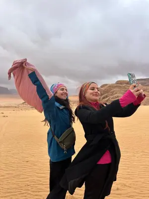 two women are taking pictures in the desert at Star Magic Camp in Wadi Rum