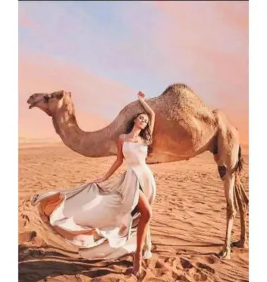 a woman in a dress posing next to a camel at Star Magic Camp in Wadi Rum