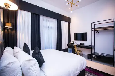 a hotel room with a white bed and a television at Hotel Philosophy in Amman