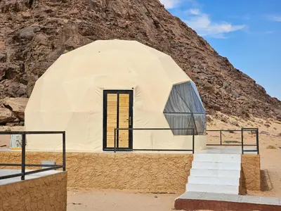 a dome house with stairs in front of a mountain at Kylie magic camp in Wadi Rum