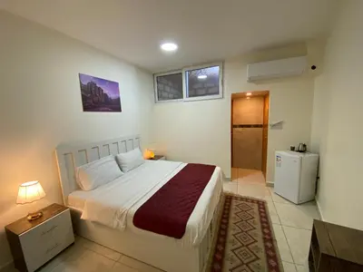 a bedroom with a large bed and a refrigerator at Rose city inn in Wadi Musa