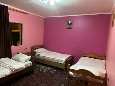 a room with two beds and a purple wall at Jordanian Baity Apartment in Wadi Musa