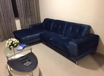 a blue couch in a living room with a table at Uptown Hotel Apartment in Amman