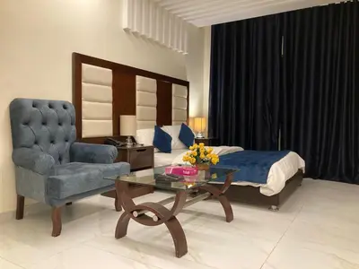 a bedroom with a bed and a chair and a table at Uptown Hotel Apartment in Amman