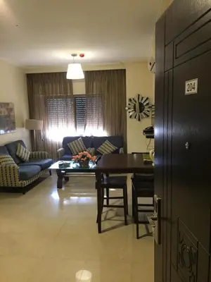 a living room with a table and a couch at Uptown Hotel Apartment in Amman