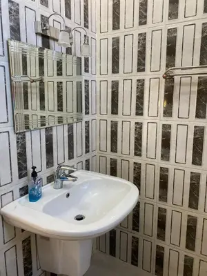 a white sink in a bathroom with black and white tiles at Jerash air apartment in Jerash