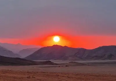 a sunset in the desert with mountains in the background at The sun of Wadi Rum camp in Wadi Rum
