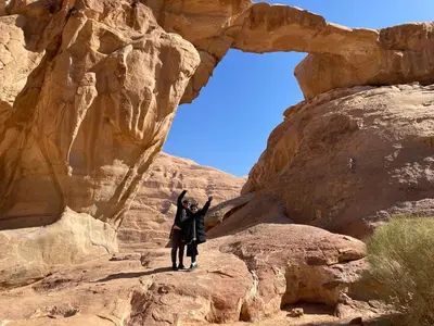 two people standing on a rock in the desert at The sun of Wadi Rum camp in Wadi Rum