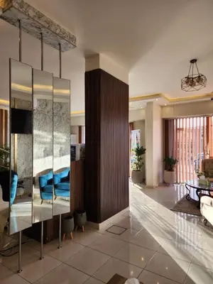 a living room with a large glass cabinet with blue pillows at Aster Hotel Aqaba in Aqaba