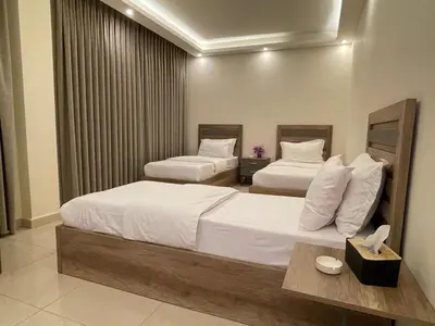 a hotel room with two beds with white sheets at Aster Hotel Aqaba in Aqaba