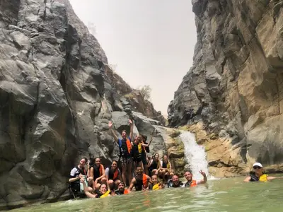 a group of people standing in the water in a waterfall at Alhidan Hostel & adventure in Madaba