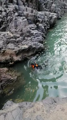 a person in the water next to some rocks at Alhidan Hostel & adventure in Madaba