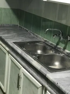 a stainless steel sink in a kitchen with green tiles at Elite Furnished Apartment in Wadi Musa
