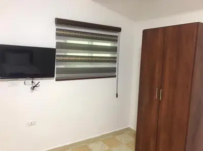 a room with a flat screen tv and a wooden cabinet at Elite Furnished Apartment in Wadi Musa