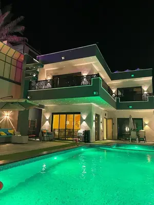 a large swimming pool in front of a house at night at Villa Jana Chalet in Ash Shāghūr