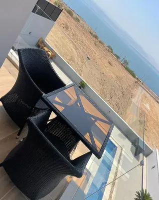 a table and chairs on a balcony with a view of the ocean at Follow Sea Villa in Sowayma
