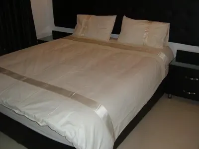 a large bed with white sheets and pillows at The Place Apartments in Amman