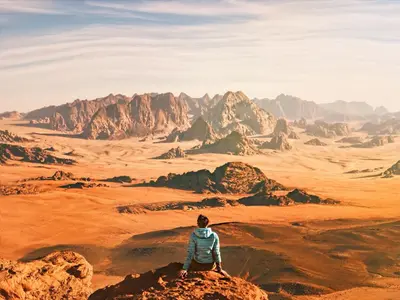 a man sitting on a rock looking at the desert at Mohammed Mutlak Camp in Wadi Rum