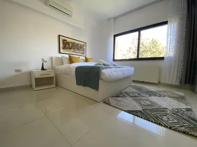 a white bedroom with a bed and a window at Lemon Tree Residence in Amman