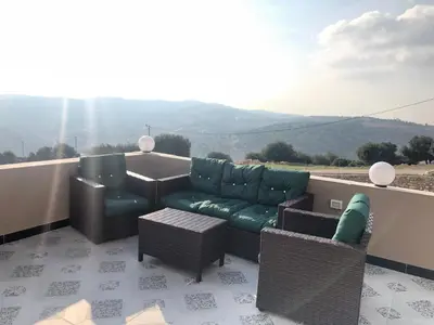 a living room with a couch and chairs on a balcony at Abu Hossam s chalet in Jerash