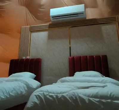 a room with two beds and a tv on the wall at Jawharat Rum camp in Wadi Rum